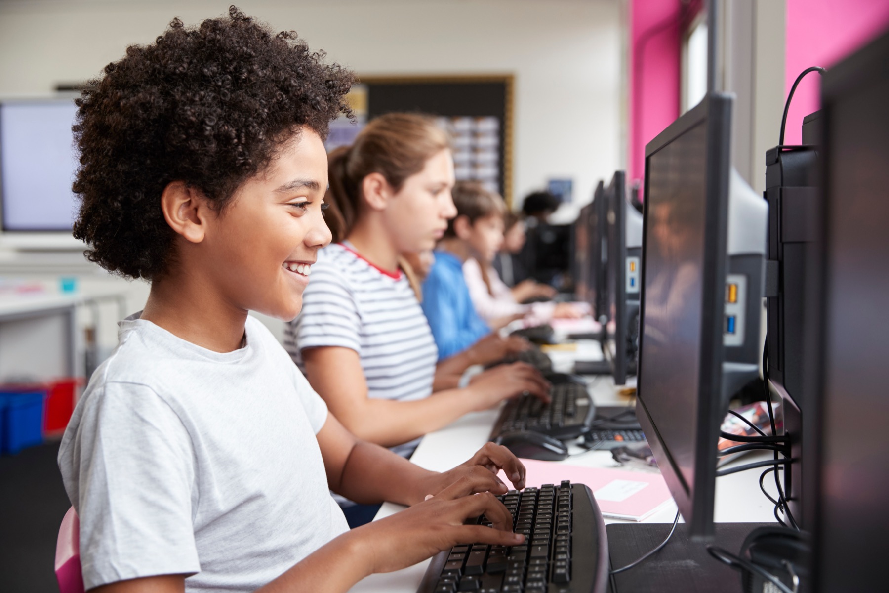 Students smiling while writing computer code in a school computer lab